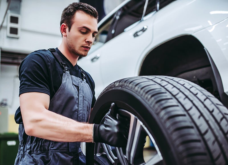 Mechanic inspecting and rotating a car tire